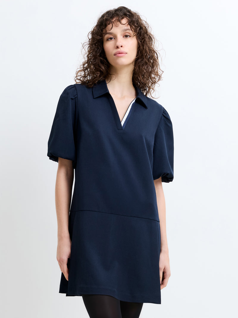 Woman wearing a navy blue, pleated mini dress